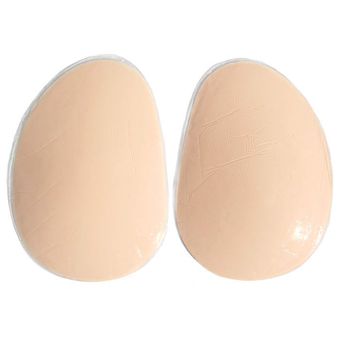 A pair of beige silicone adhesive butt/hip pads on a white background.