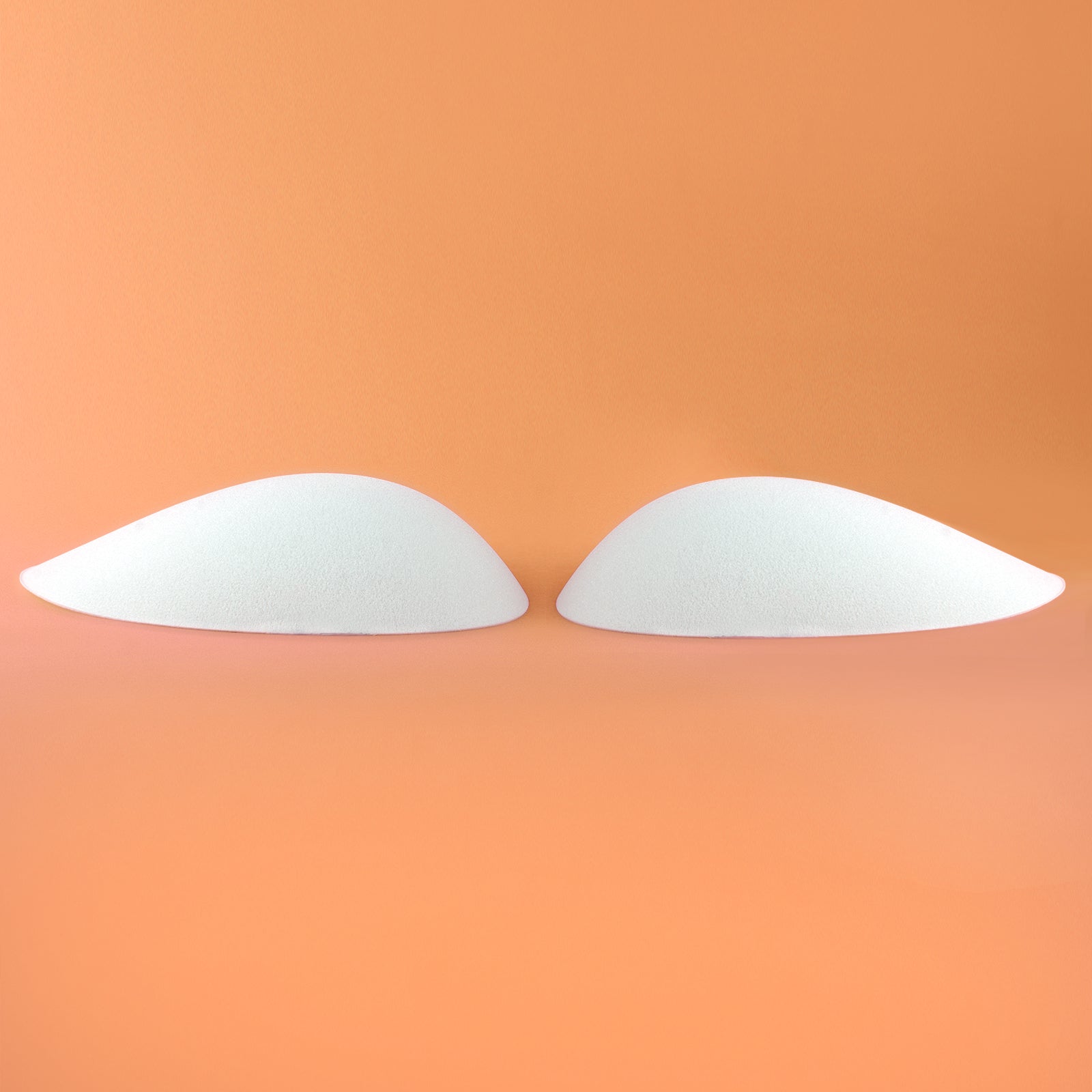 A pair of thick white foam pads for butt or hips. Side view.